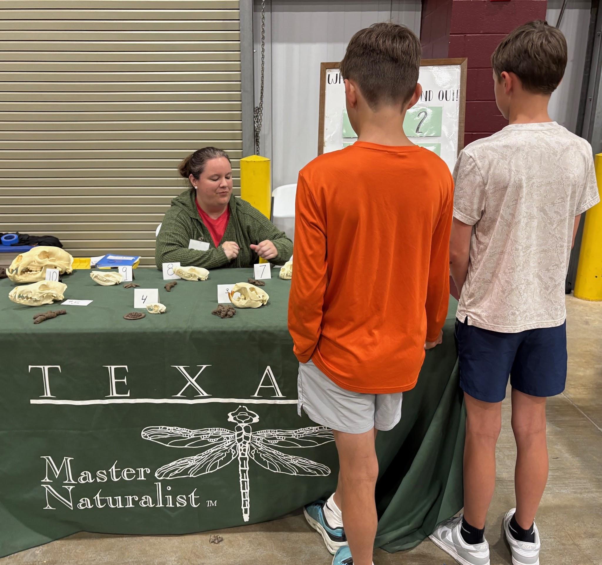Texas Master Naturalist volunteer speaking with young visitors at Champions for Nature
