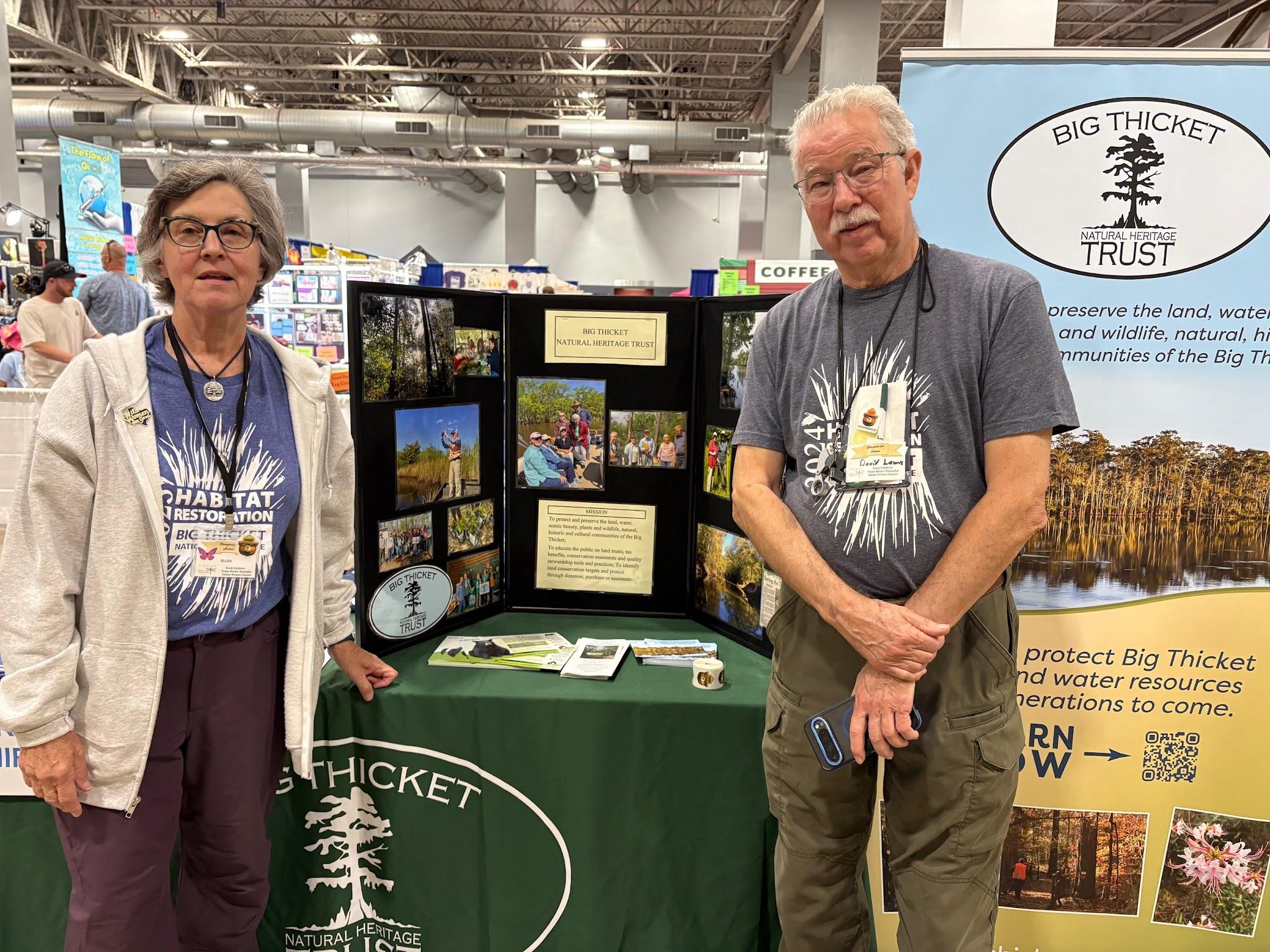 Two volunteers standing at a Big Thicket outreach table at Champions for Nature