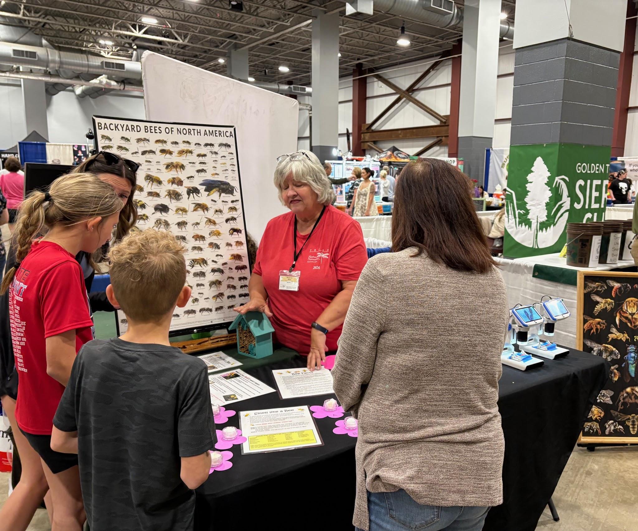 Visitors talking with a volunteer at a Champions for Nature outreach table